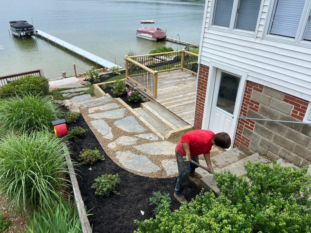 Christian Brothers Lawncare and Outdoor Services crew member installing landscape plants on a waterfront property