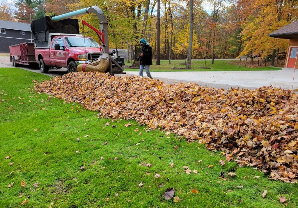 Christian Brothers truck cleaning up a raked pile of leaves for lawn maintenance
